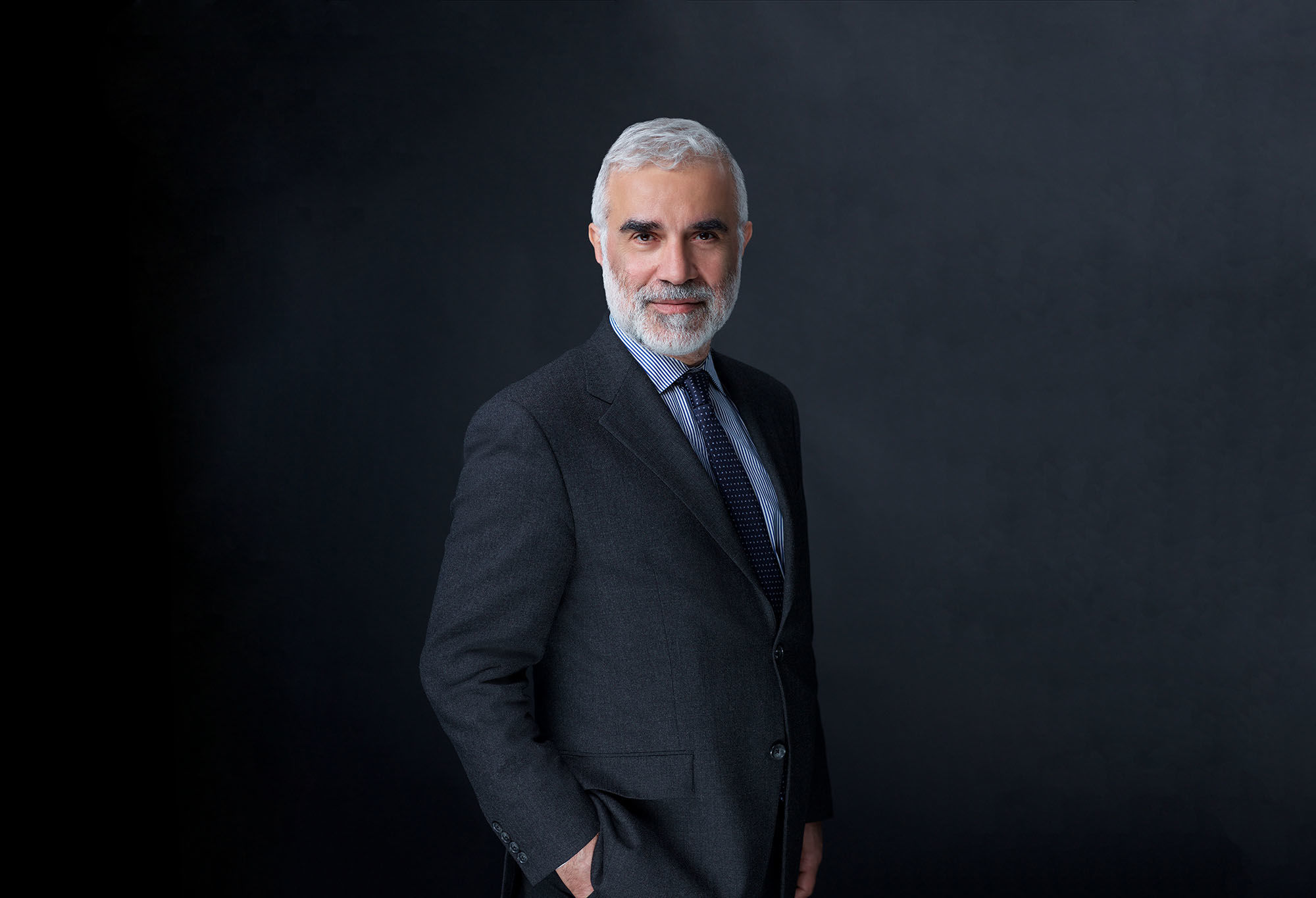 Corporate headshot NYC — executive with gray beard in dark suit, charcoal studio background