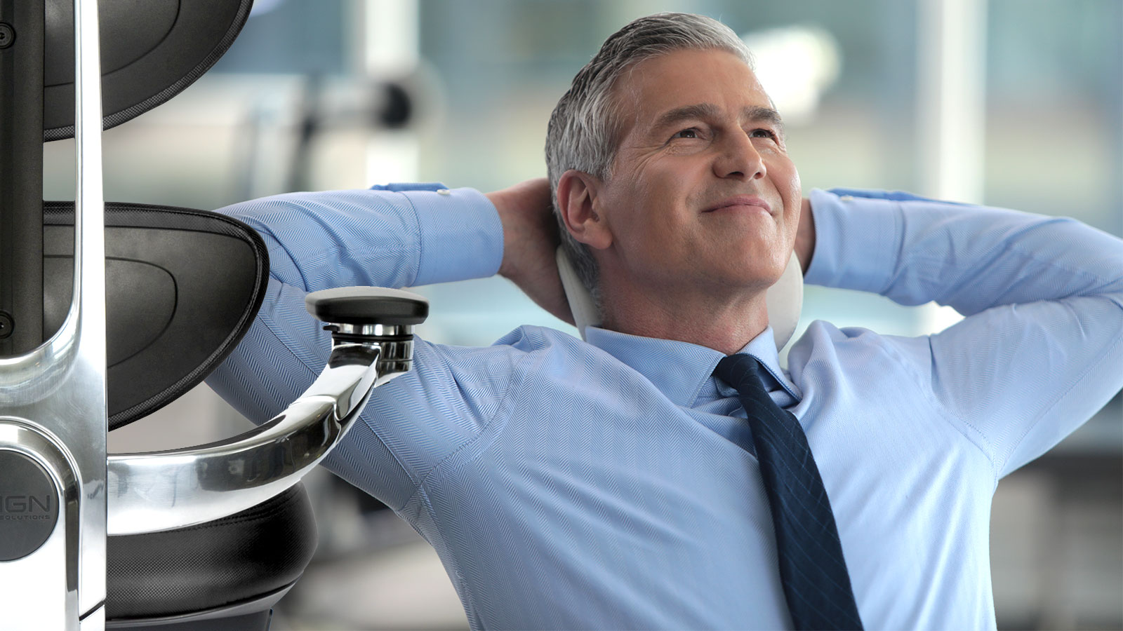 Corporate lifestyle photography — businessman relaxing at his desk, hands behind head